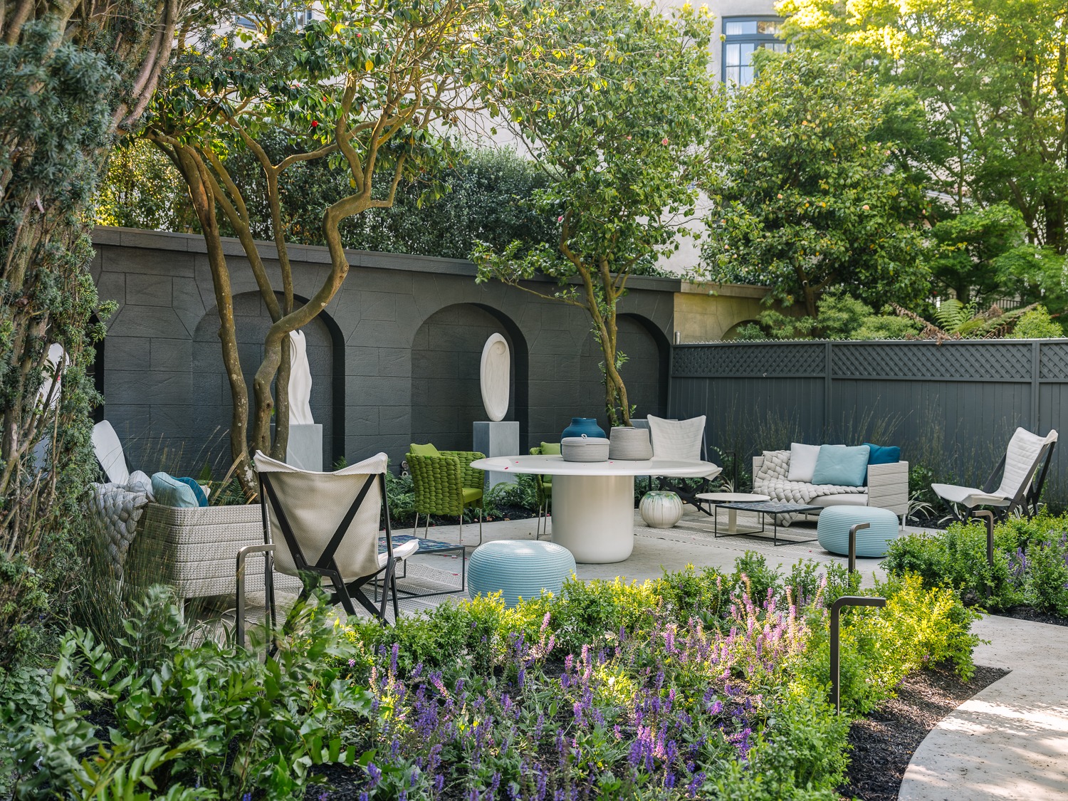 Outdoor seating area at Le Petit Trianon with smaller Yoko Kubrick marble sculptures installed within dark architectural niches
