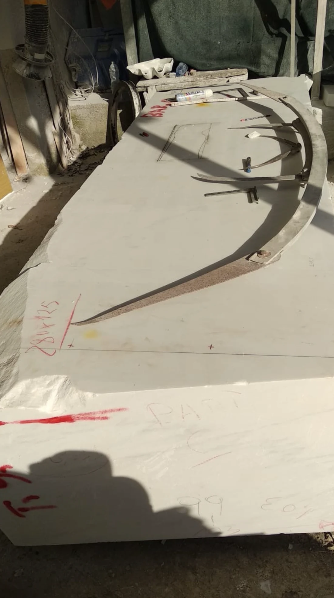 A large rough block of Michelangelo marble with old curved measuring and layout tools lying across its surface