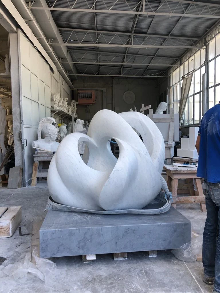 A monumental marble sculpture standing in a working atelier in Pietrasanta
